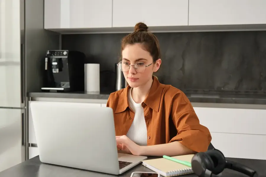 Portrait of young concentrated woman in glasses selfemployed freelancer working from home on laptop