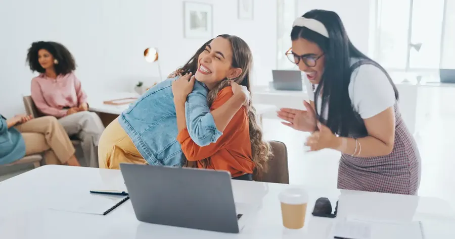 Laptop success or women high five at work in celebration of digital marketing sales goals or kpi target Happy winner or excited employees hugging to celebrate bonus business growth or achievement